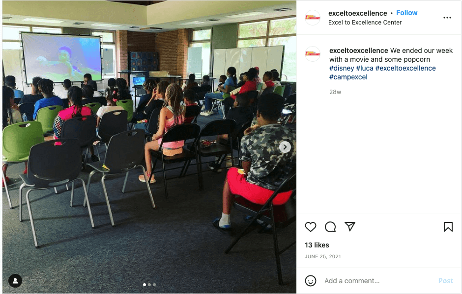The image is showing people sitting on a chair watching something on a projector.